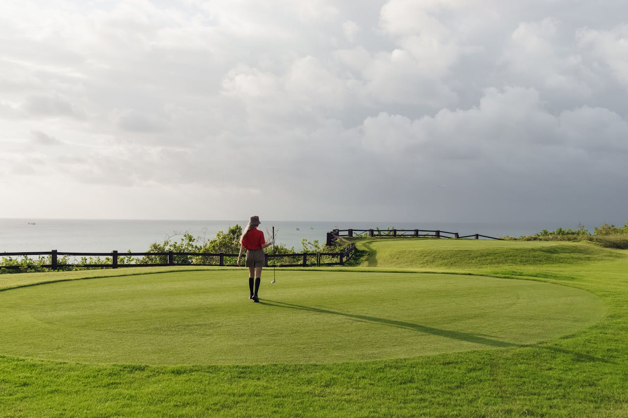 Offerings A woman playing golf on a scenic coastal golf course under a partly cloudy sky.